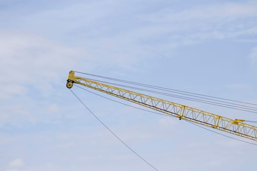 Crane lifts old yellow with blue sky.