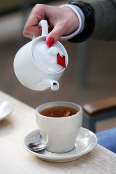 White tea teapot and female hand