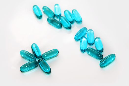 Blue capsules on white background close up
