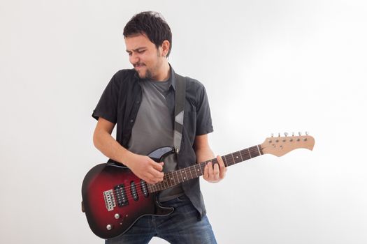 young man jumping with electric guitar on white background