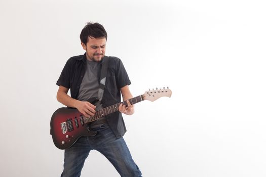 young man jumping with electric guitar on white background