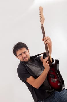 young man jumping with electric guitar on white background