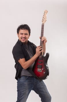 young man jumping with electric guitar on white background