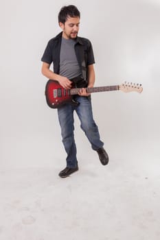 young man jumping with electric guitar on white background