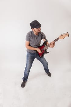 young man jumping with electric guitar on white background