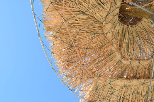 Straw parasols at the beach in summer