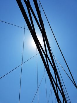 Bridge suspension cables against blue sky and sun.