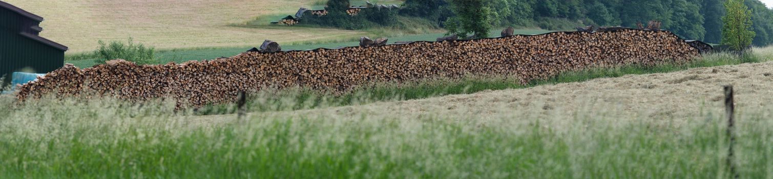 Beautifully stacked firewood stock for winter on a large meadow in the countryside.