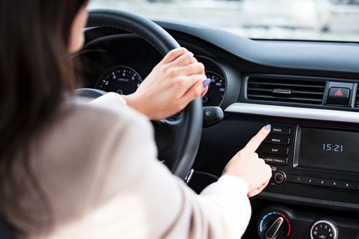 Woman pressing radio button on car's control panel