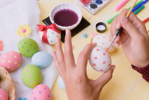 Happy easter! A woman hand painting Easter eggs. Happy family preparing for Easter.