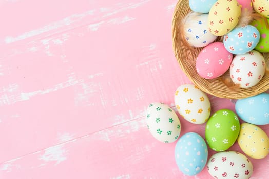 Happy easter! Colorful of Easter eggs in nest with paper star, flower and Feather on pastel color bright pink and white wooden background.