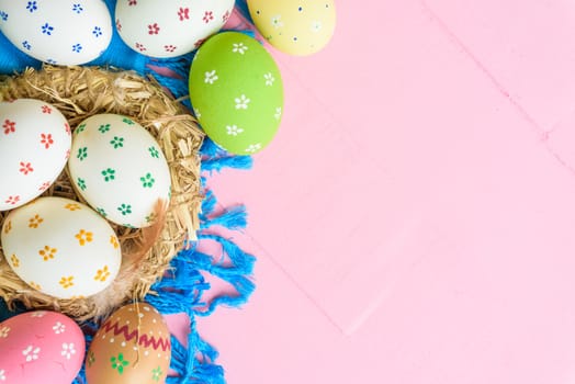 Happy easter! Colorful of Easter eggs in nest with paper star, flower and Feather on pastel color bright pink and white wooden background.