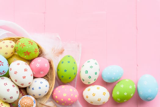 Happy easter! Colorful of Easter eggs in nest with paper star, flower and Feather on pastel color bright pink and white wooden background.