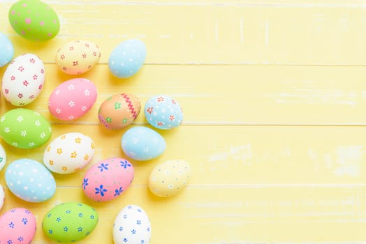 Happy easter! Colorful of Easter eggs on pastel color bright yellow and white wooden background.