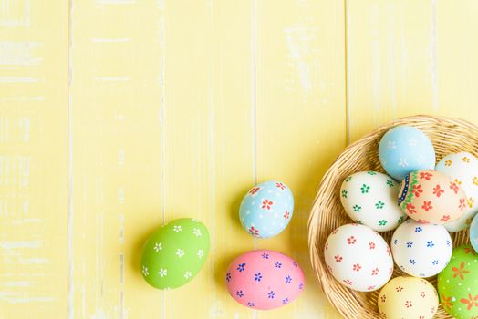 Happy easter! Colorful of Easter eggs in nest with red ribbon, Feather and paper star on pastel color bright yellow and white wooden background.