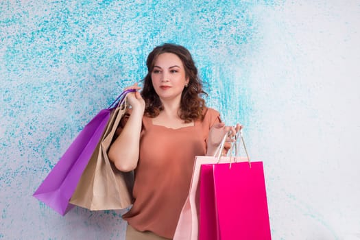 Smiling woman at shopping holding colourful paper bags in both hands