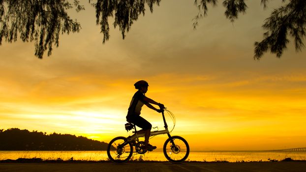 Silhouette of cyclist at sunset or sunrise near ocean