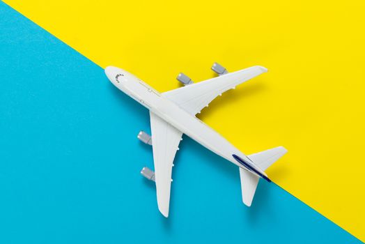 Miniature airplane model on blue and yellow background for travel theme