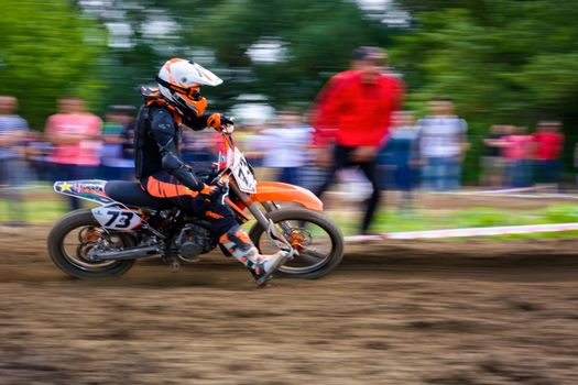 Uzhgorod, Ukraine - May 21, 2017: MX rider turns on a corner. Motion blur with flying dirt. TransCarpathian regional Motocross Championship