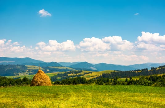 haystack on a grassy field on top of a hill. beautiful mountainous countryside scenery in summer
