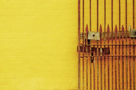 Rusty antique lock gate and bright yellow wall