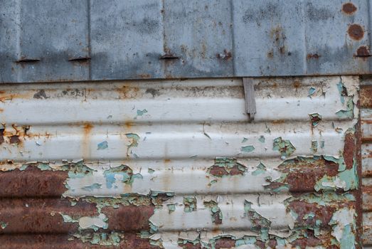 rusty iron surface covered with old chipped grey color paint, which has long been influenced by different climatic conditions