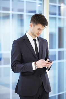 Businessman looking at his smartphone in modern building