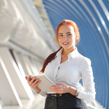 Beautiful modern businesswoman holding tablet computer inside modern building