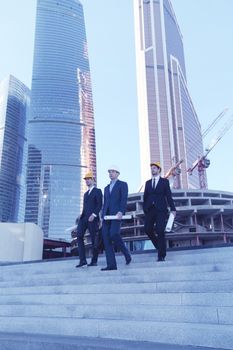 Architects with blueprint at skyscrapers background