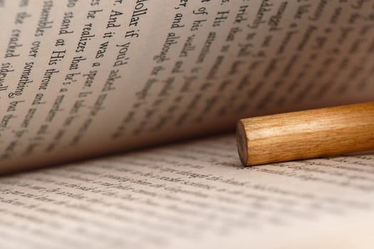 close-up of an open book with a pencil inside