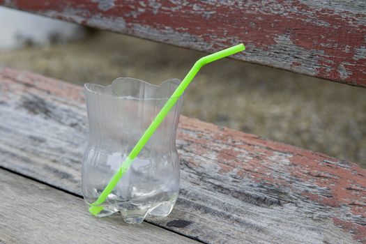 Clear plastic glass with green tube on the wooden desk.