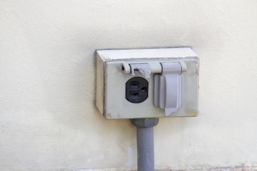 The old electrical plug next to the cream wall.