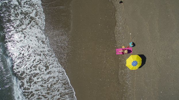 AERIAL: Pretty young woman sunbathing on beach Antalya