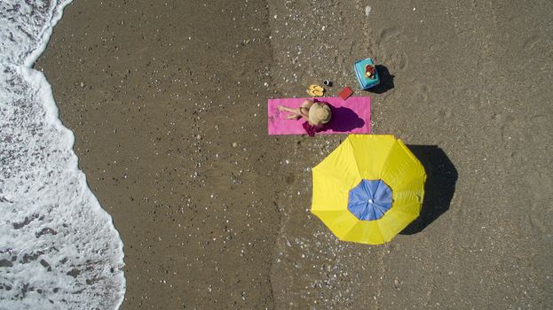 AERIAL: Pretty young woman sunbathing on beach Antalya