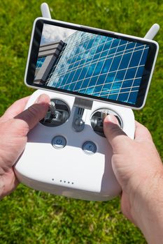 Hands Holding Drone Quadcopter Controller With Corporate Building on Screen.