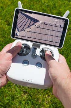 Hands Holding Drone Quadcopter Controller With Residential Roof Image on Screen.