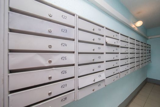 row of gray mailboxes in corridor of apartment building