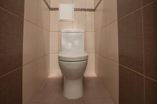 Toilet bowl in the toilet room. Restroom with brown tile decoration
