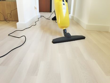 close up view of an electric broom cleaning a wooden floor