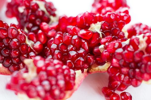 Cut-up dissected tasty garnet fruit pomegranate with rolled out seeds isolated on white background
