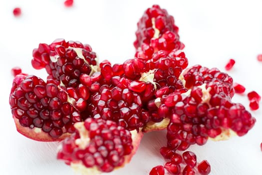 Cut-up dissected tasty garnet fruit pomegranate with rolled out seeds isolated on white background