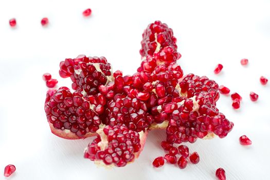 Cut-up dissected tasty garnet fruit pomegranate with rolled out seeds isolated on white background