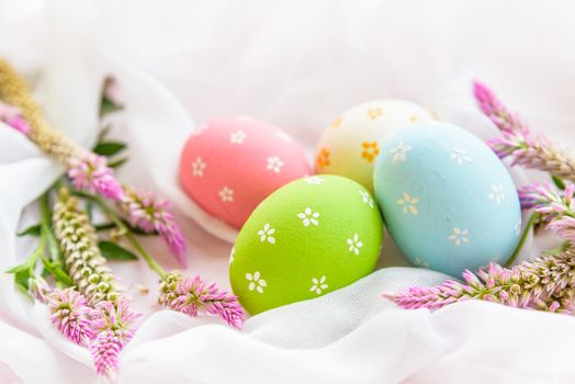Happy easter! Colorful of Easter eggs in nest with flower,  paper star and Feather on white cheesecloth background.