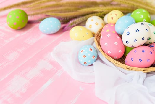 Happy easter! Colorful of Easter eggs in nest with paper star, flower and Feather on pastel color bright pink and white wooden background.