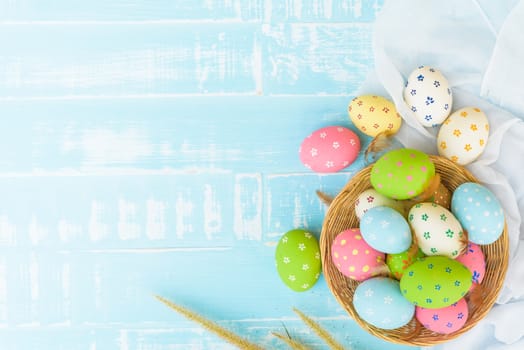 Happy easter! Colorful of Easter eggs in nest with paper star, flower and Feather on pastel color bright blue and white wooden background.