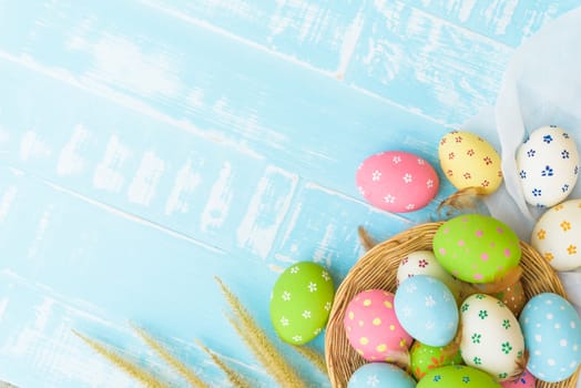 Happy easter! Colorful of Easter eggs in nest with paper star, flower and Feather on pastel color bright blue and white wooden background.