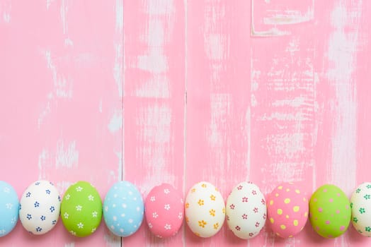 Happy easter! Row Easter eggs with colorful paper flowers on bright pink wooden background.