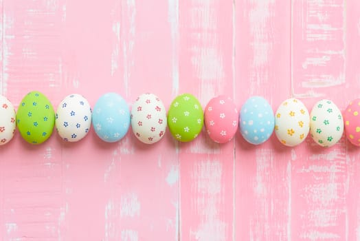 Happy easter! Row Easter eggs with colorful paper flowers on bright pink wooden background.