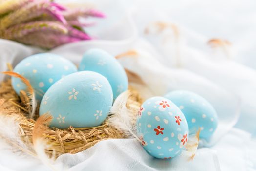 Happy easter! Colorful of Easter eggs in nest with flower,  paper star and Feather on white cheesecloth background.