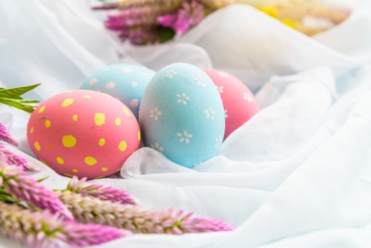 Happy easter! Colorful of Easter eggs in nest with flower,  paper star and Feather on white cheesecloth background.